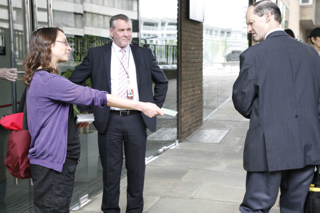 Activist Mel Strickland hands leaflet against Shell to a shareholder outside Shell AGM