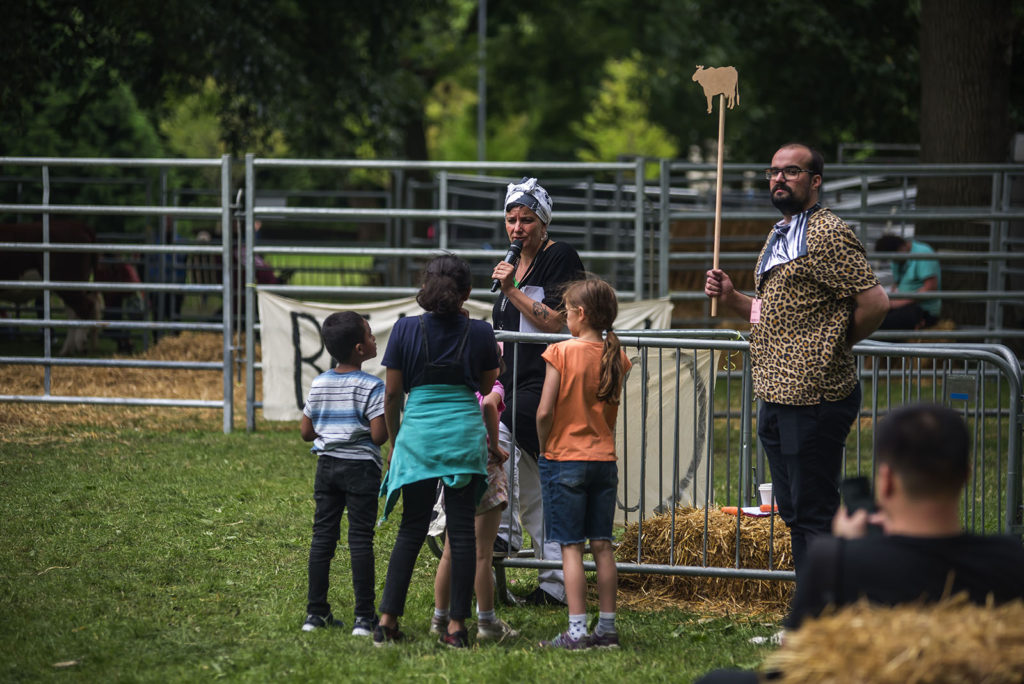 "Sibylle Peters inside a pen similar to the cow mayors with Christopher Weymann (Theatre of Research) and children who have signed up to the Animalship registration of our alternative city, sharing comments and questions with the public. "